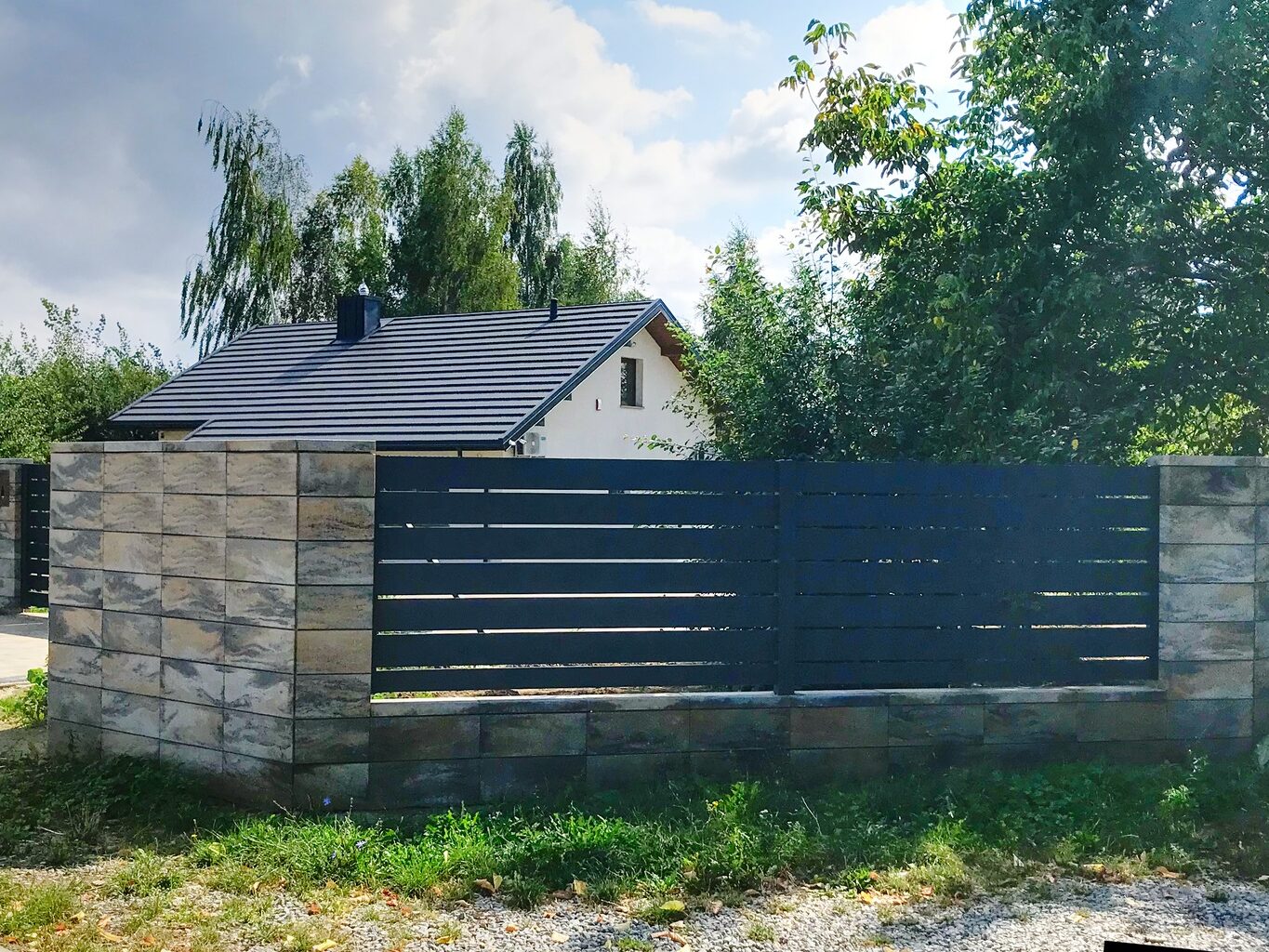 Ogrodzenia aluminiowe otoczone zielenią.