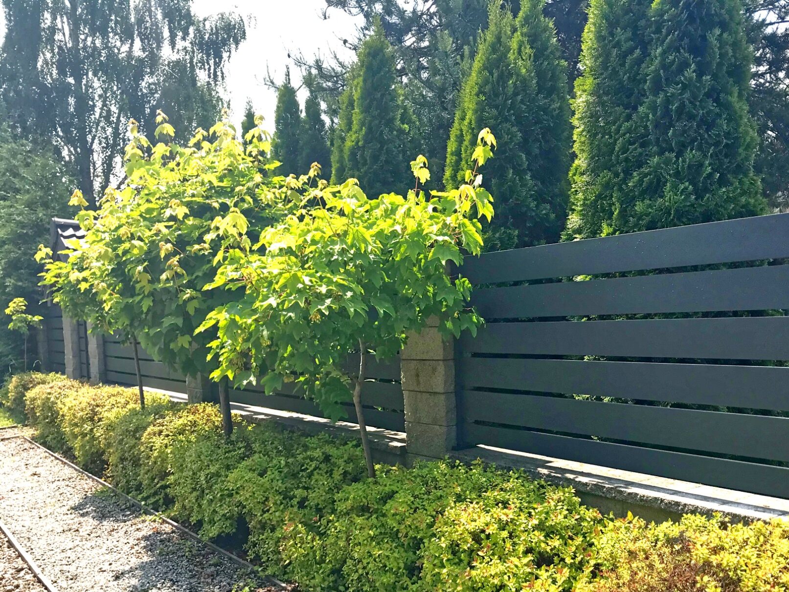 Przykład ogrodzeń aluminiowych palisadowych z poziomymi przęsłami - wokół piękny ogród. Palisady są z estetycznego bloczku kamiennego.