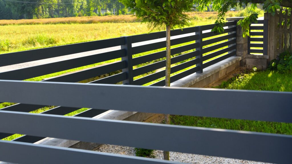 Ogrodzenia aluminiowe są świetnym rozwiązaniem dla małych działek - na zdjęciu widać integrację z istniejącym już kamiennym ogrodzeniem. 